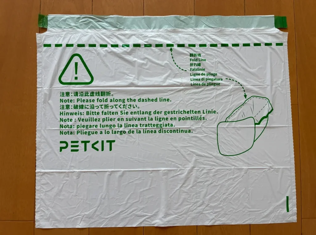 床に広げたPETKITの専用のゴミ袋。緑の破線と、破線に沿って折るようにという注意書きが入っている