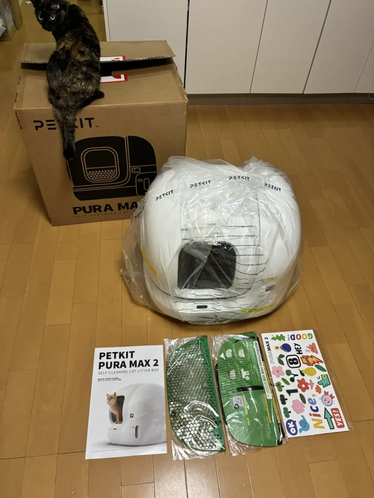 届いたPETKIT Pura Max 2の本体と箱、クイックスタートガイド、部品、ステッカー。箱の上にサビ猫